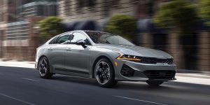 Front profile view of a silver 2022 Kia K5 being driven on the road. | Kia dealer in Sherwood, AR.