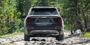 Rear view of a dark forest green 2022 Kia Sorento parked on a rocky path in a wooded area. | Kia dealer in Sherwood, AR.