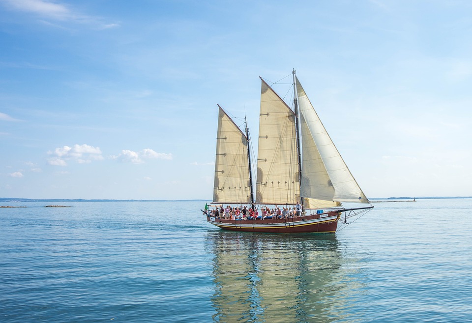 A large sail boat with several people in it on an open body of water. | Boating around Sherwood, AR. | Kia Dealership