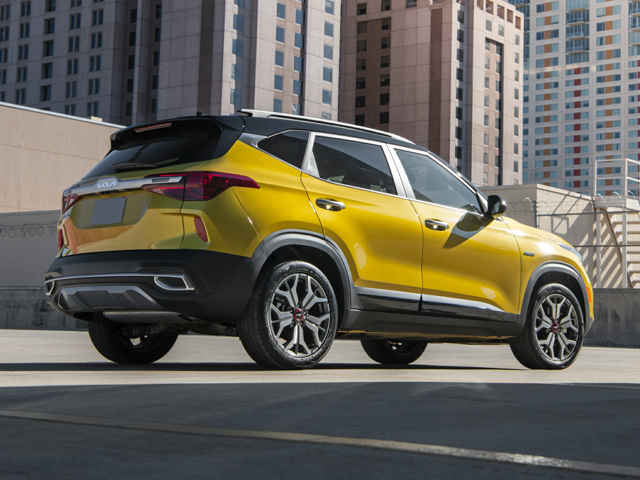 Profile view of parked, golden yellow 2023 Kia Seltos with tall buildings in the background. | Kia dealer in Sherwood, AR | Crain Kia of Sherwood